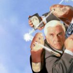The Naked Gun Movie Wallpaper with Leslie nielsen in a grey suit holding a shooting gun and a police badge