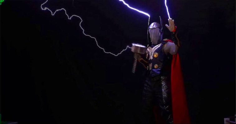 Thor cosplay guy holding electrified hammer and wearing red cape